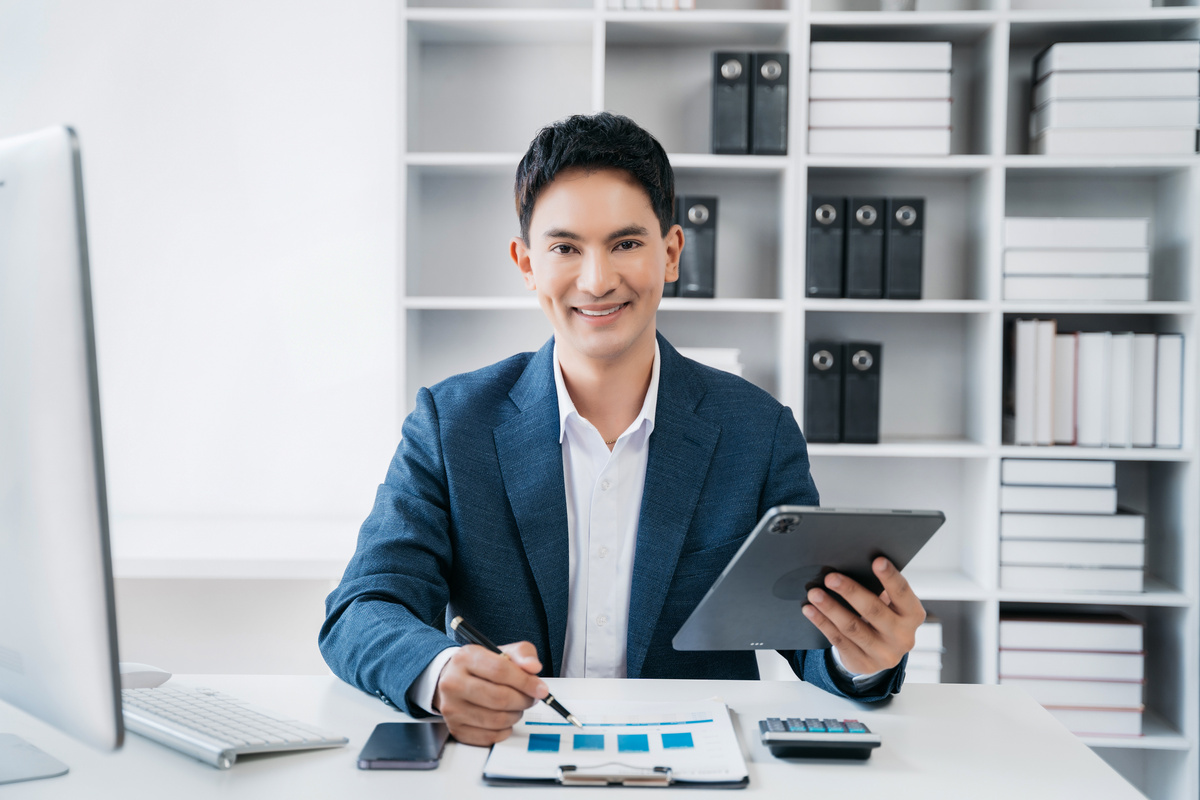 Male asian sitting at the desk, looking to camera.